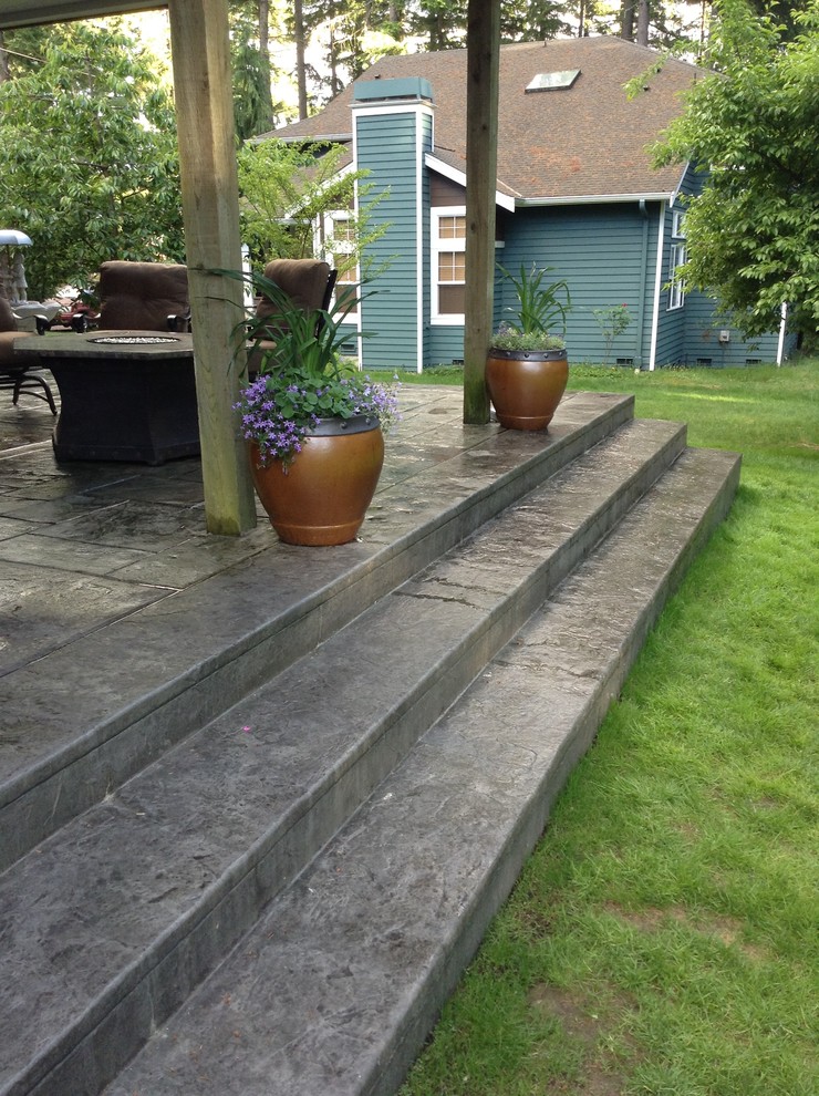 This is an example of a medium sized classic back patio in Seattle with a fire feature and stamped concrete.