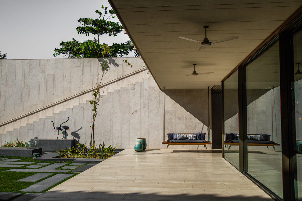 Example of a huge trendy backyard tile patio design in Ahmedabad with a roof extension