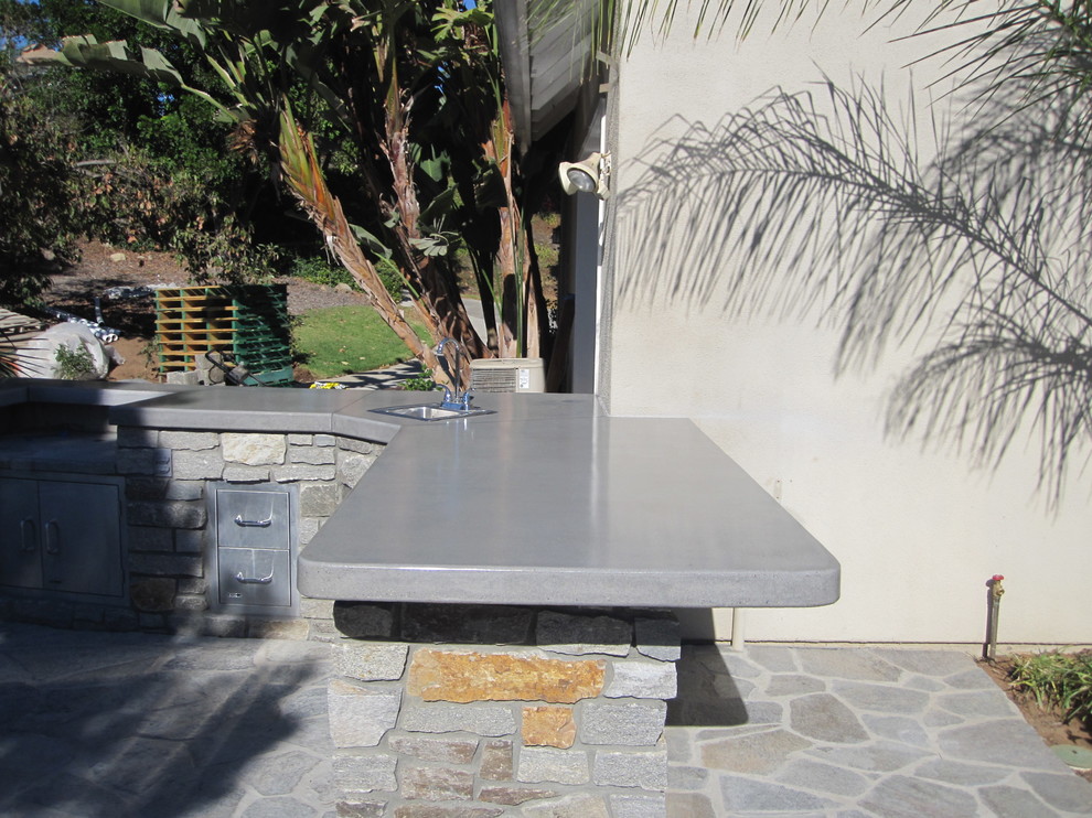 Photo of a large world-inspired back patio in San Diego with an outdoor kitchen, natural stone paving and no cover.