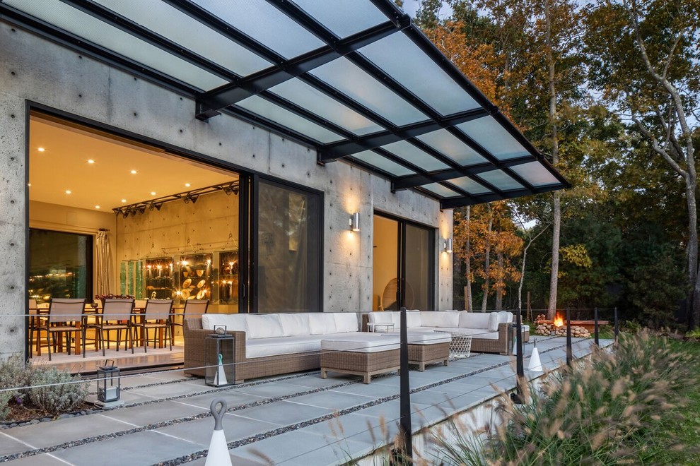 Photo of a large contemporary back patio in New York with a potted garden, concrete paving and an awning.