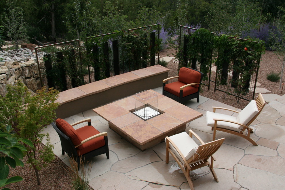 Cette photo montre une terrasse arrière tendance avec un foyer extérieur et des pavés en pierre naturelle.