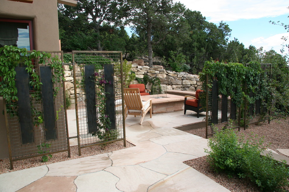 Cette photo montre une terrasse arrière tendance avec un foyer extérieur et des pavés en pierre naturelle.