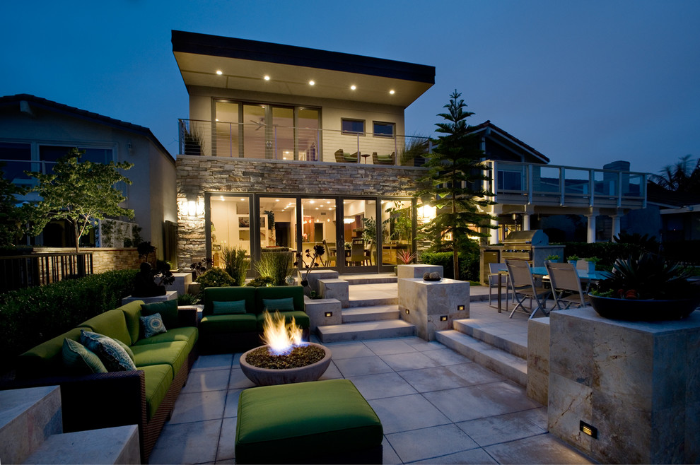 Exemple d'une terrasse arrière tendance avec un foyer extérieur.