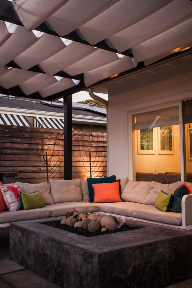 Esempio di un grande patio o portico design dietro casa con un focolare, pavimentazioni in pietra naturale e un parasole