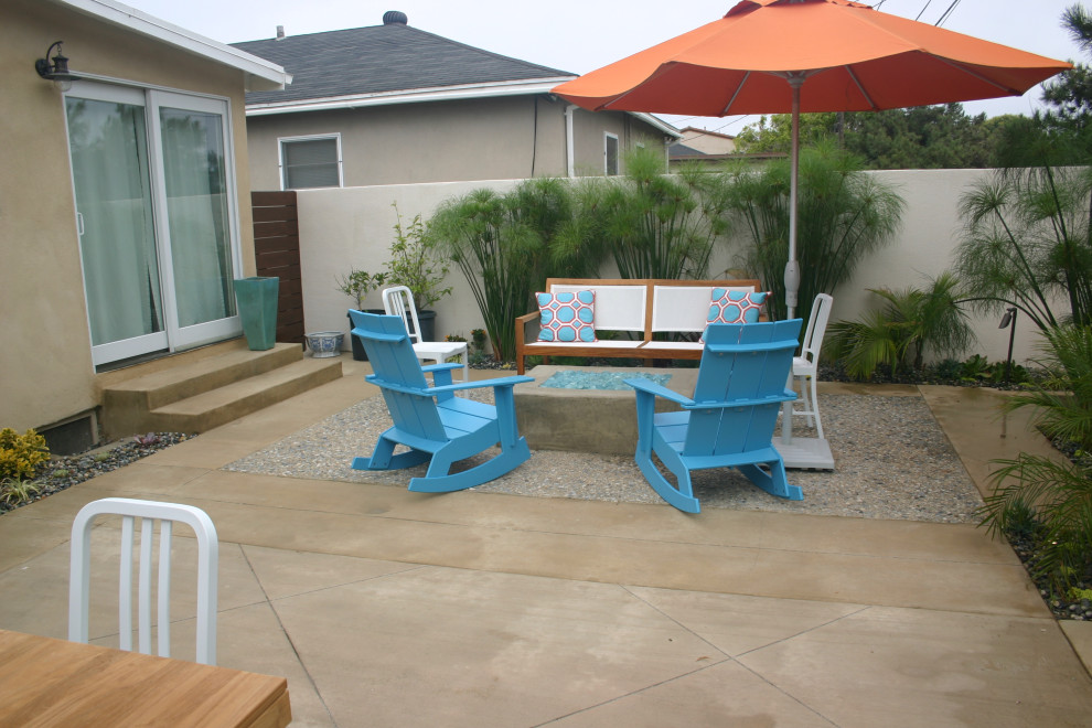 Esempio di un piccolo patio o portico costiero dietro casa con un focolare e lastre di cemento
