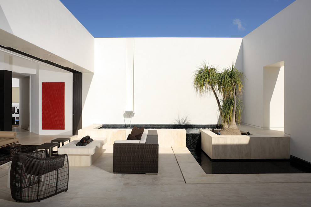 Example of a mid-sized trendy courtyard concrete paver patio design in Orange County with a fire pit and no cover