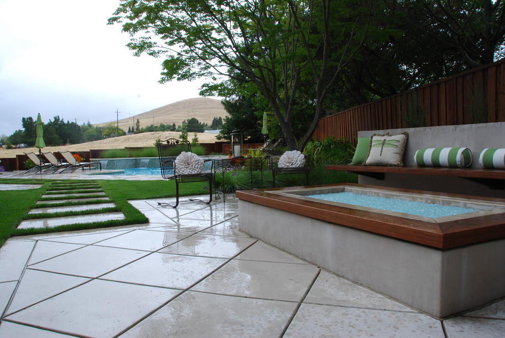 Réalisation d'une terrasse latérale design de taille moyenne avec un foyer extérieur et des pavés en béton.