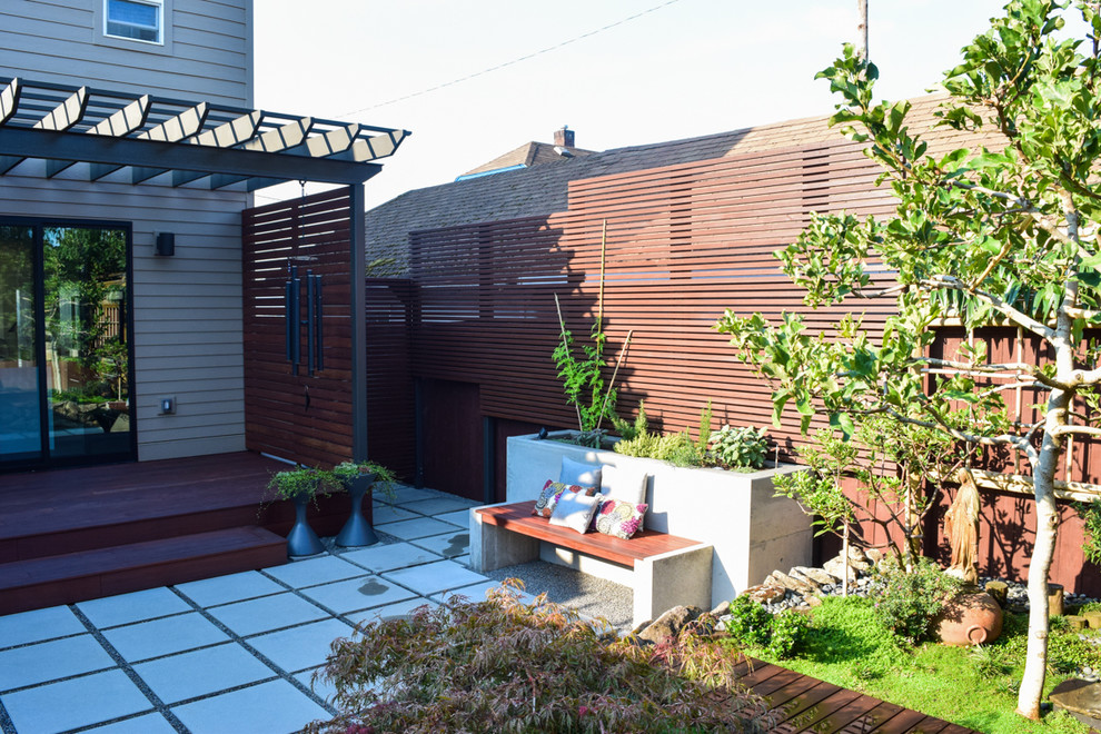 Small world-inspired back patio in Portland with a potted garden, concrete paving and a pergola.