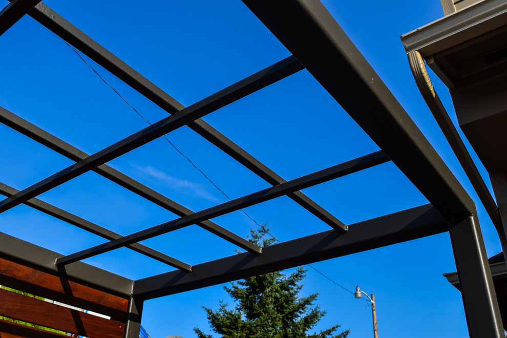 This is an example of a small world-inspired front patio in Portland with a living wall, concrete paving and a pergola.