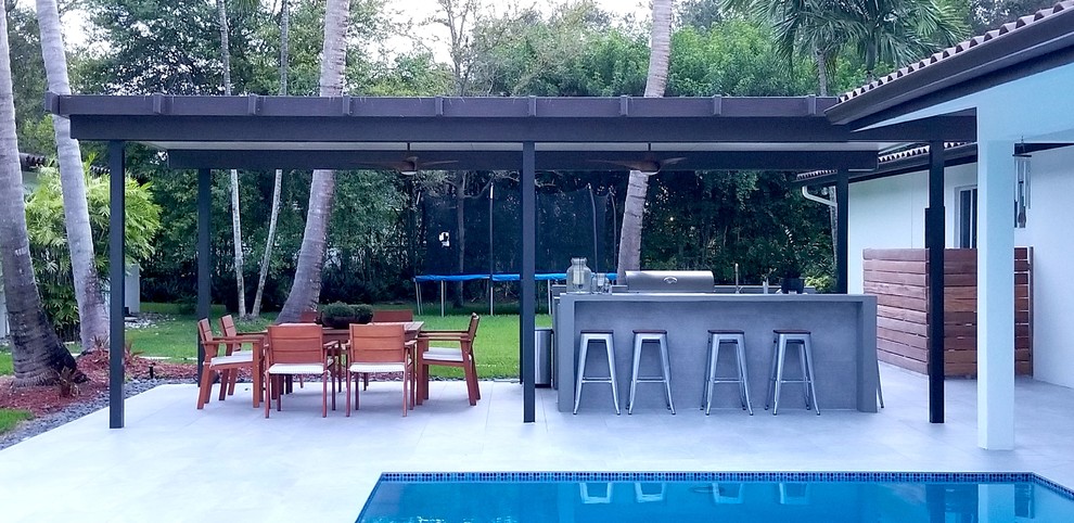 This is an example of a medium sized contemporary back patio in Miami with an outdoor kitchen, concrete paving and a roof extension.
