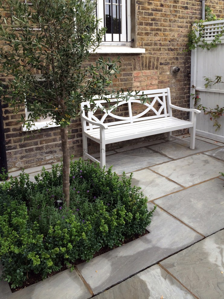 This is an example of a medium sized contemporary back patio in London with natural stone paving.