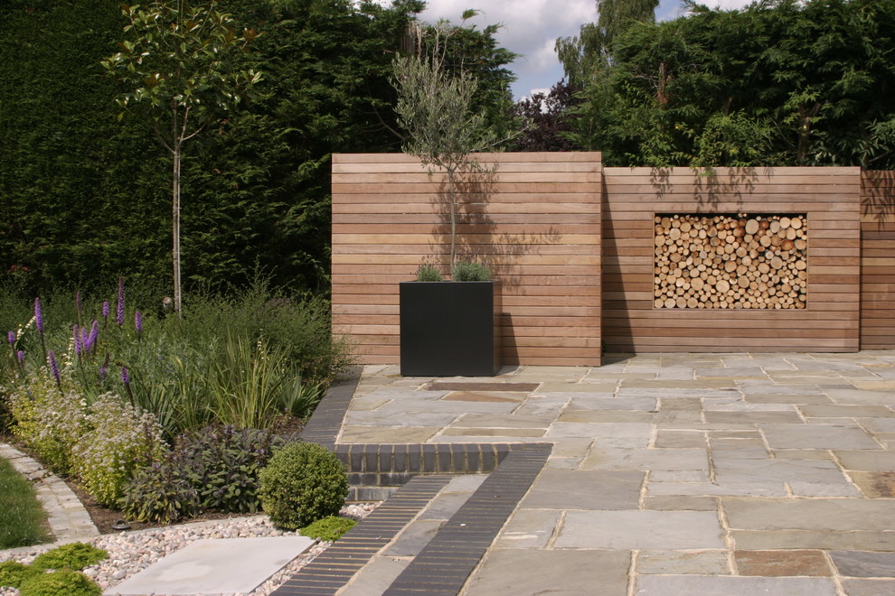 Design ideas for a large contemporary back patio in Berkshire with natural stone paving and no cover.
