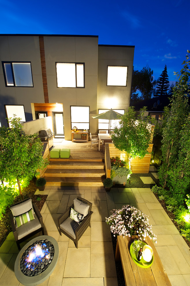 This is an example of a small contemporary back patio in Calgary with a fire feature, concrete paving and no cover.