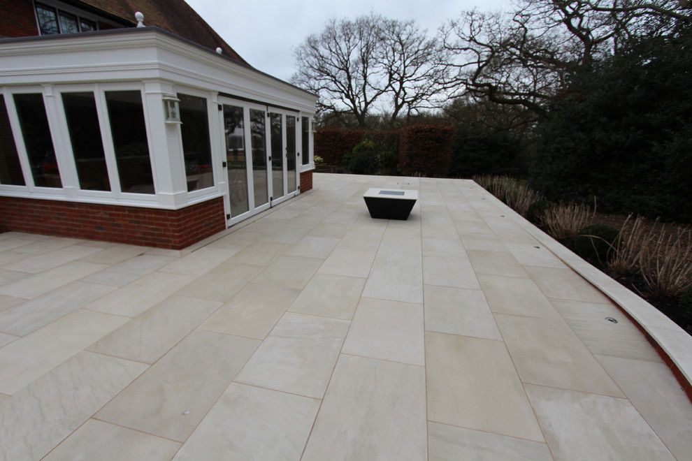 This is an example of a large contemporary back patio in Essex with natural stone paving.