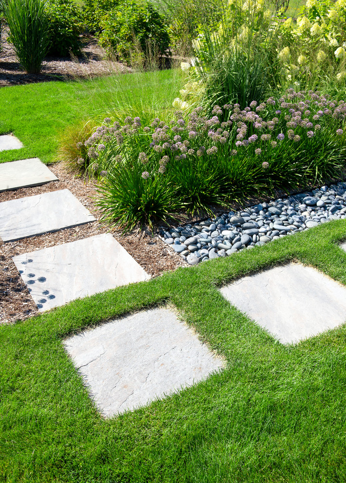 This is an example of a large modern side garden in Milwaukee with natural stone paving.