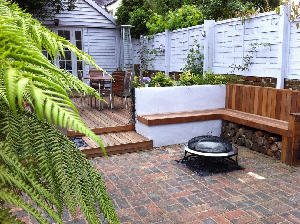 Immagine di un patio o portico minimal con pavimentazioni in mattoni e un focolare