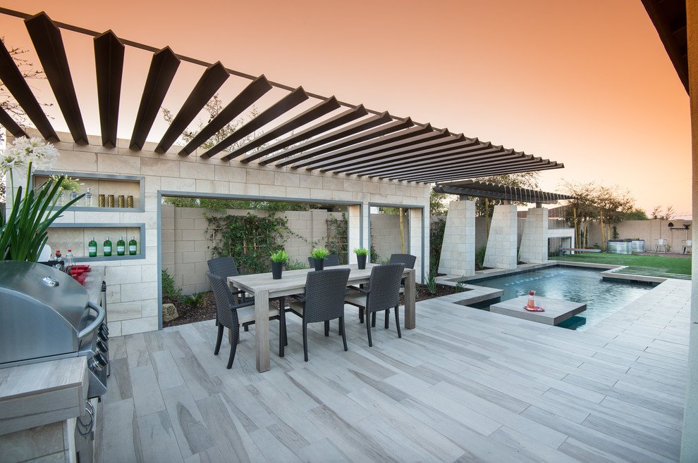 This is an example of a contemporary back patio in Phoenix with a pergola and a bar area.