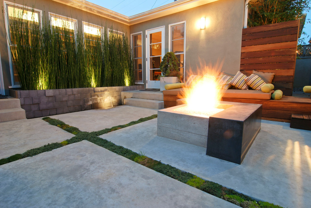 На фото: двор в современном стиле с местом для костра и покрытием из бетонных плит без защиты от солнца