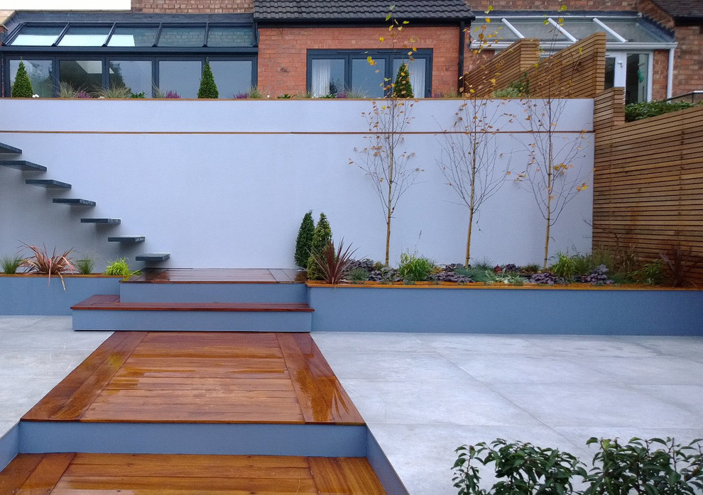 Large contemporary back patio in West Midlands with a water feature and tiled flooring.