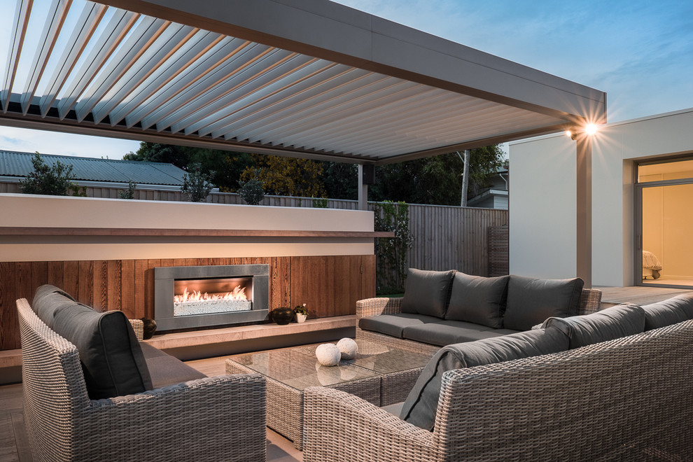 Contemporary back patio in Christchurch with a pergola and a fireplace.