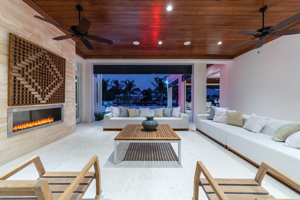 This is an example of a contemporary back patio in Miami with a fireplace and a roof extension.