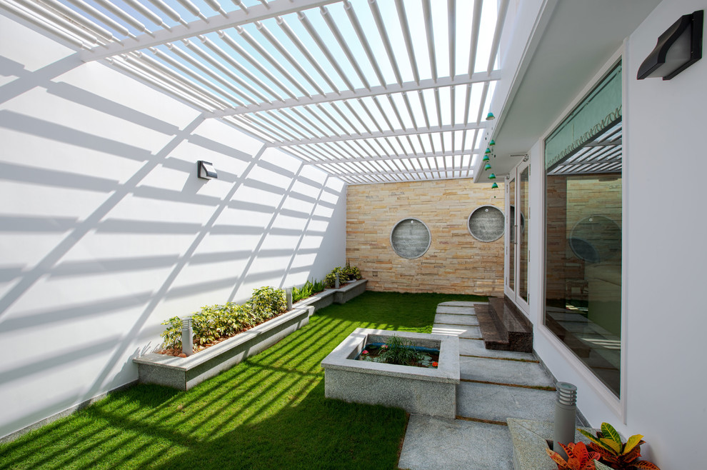 Immagine di un patio o portico design con pavimentazioni in cemento e una pergola