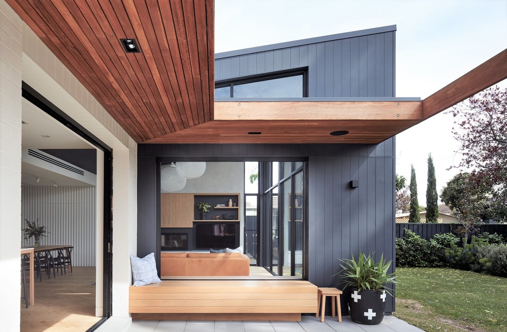 Esempio di un patio o portico design dietro casa con lastre di cemento e un tetto a sbalzo