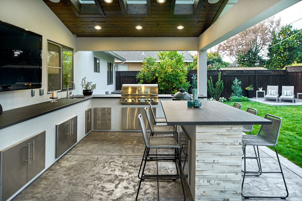 Cette image montre une grande terrasse arrière design avec une cuisine d'été, une dalle de béton et une extension de toiture.
