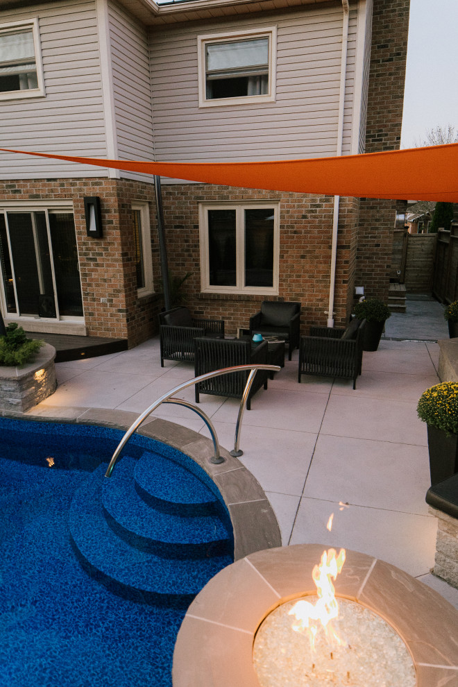Immagine di un patio o portico contemporaneo di medie dimensioni e dietro casa con lastre di cemento e un parasole