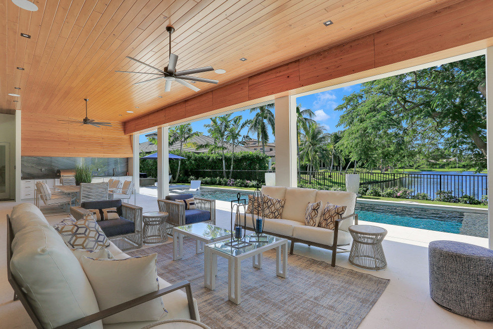 Photo of an expansive contemporary back patio in Miami with an outdoor kitchen and a roof extension.