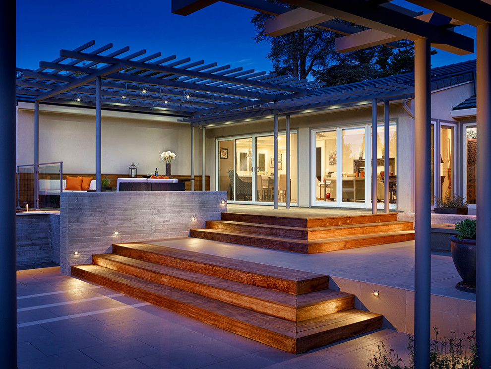 This is an example of a large contemporary back patio in San Francisco with a fire feature, a pergola and decking.