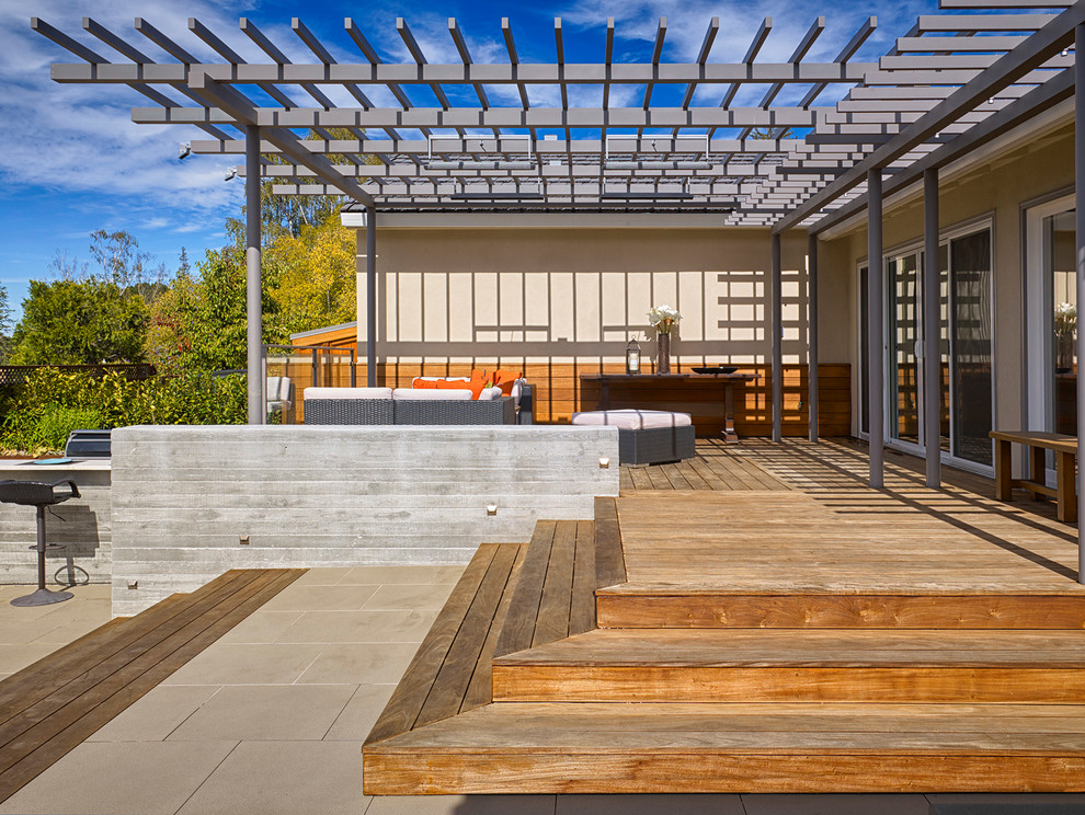 Inspiration pour une grande terrasse arrière design avec un foyer extérieur, des pavés en béton et une pergola.