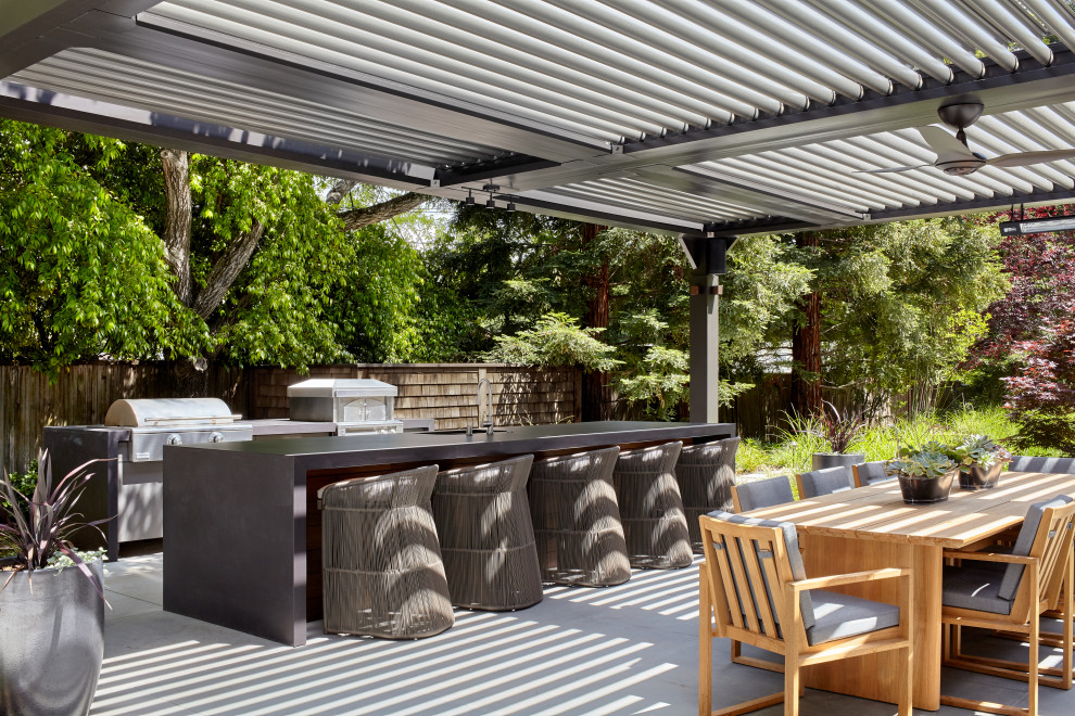 Idées déco pour une très grande terrasse arrière contemporaine avec une cuisine d'été, des pavés en pierre naturelle et une pergola.