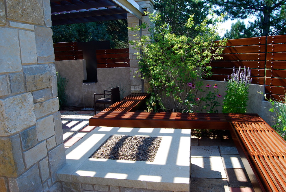 This is an example of a contemporary side patio in Denver with a fire feature, natural stone paving and a pergola.