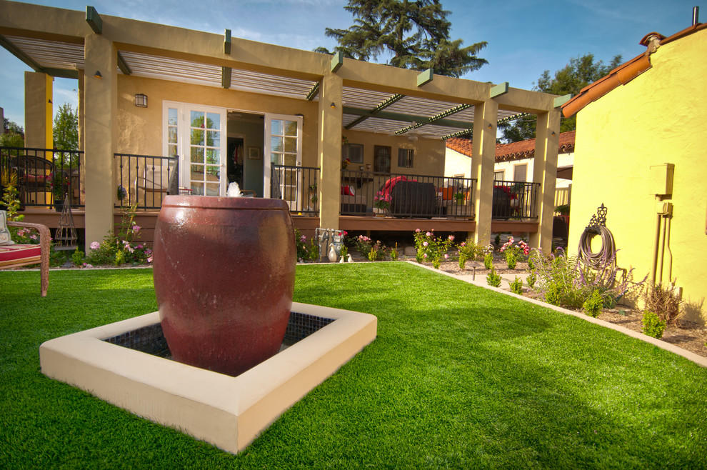 Example of a mid-sized tuscan backyard patio fountain design in Los Angeles with a pergola and decking