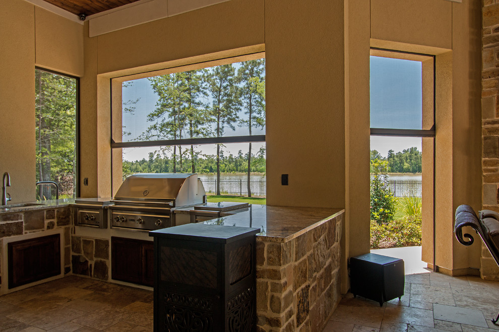 Aménagement d'une très grande terrasse arrière classique avec une cuisine d'été, des pavés en pierre naturelle et une extension de toiture.