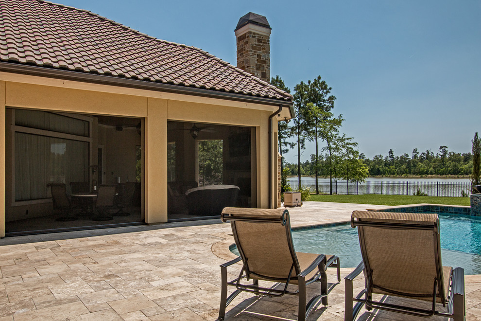 Photo of an expansive traditional back patio in Houston with an outdoor kitchen, natural stone paving and a roof extension.