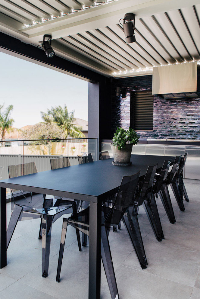 Cette photo montre une terrasse arrière tendance avec une cuisine d'été, des pavés en béton et une extension de toiture.