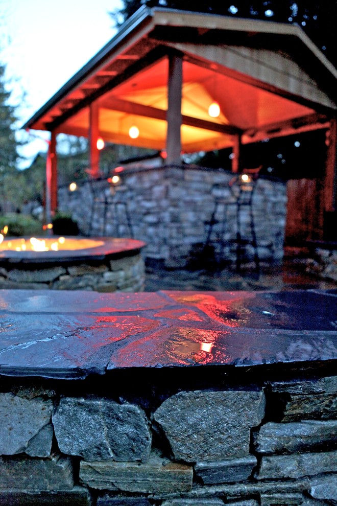 Large elegant backyard stone patio kitchen photo in Seattle with a gazebo