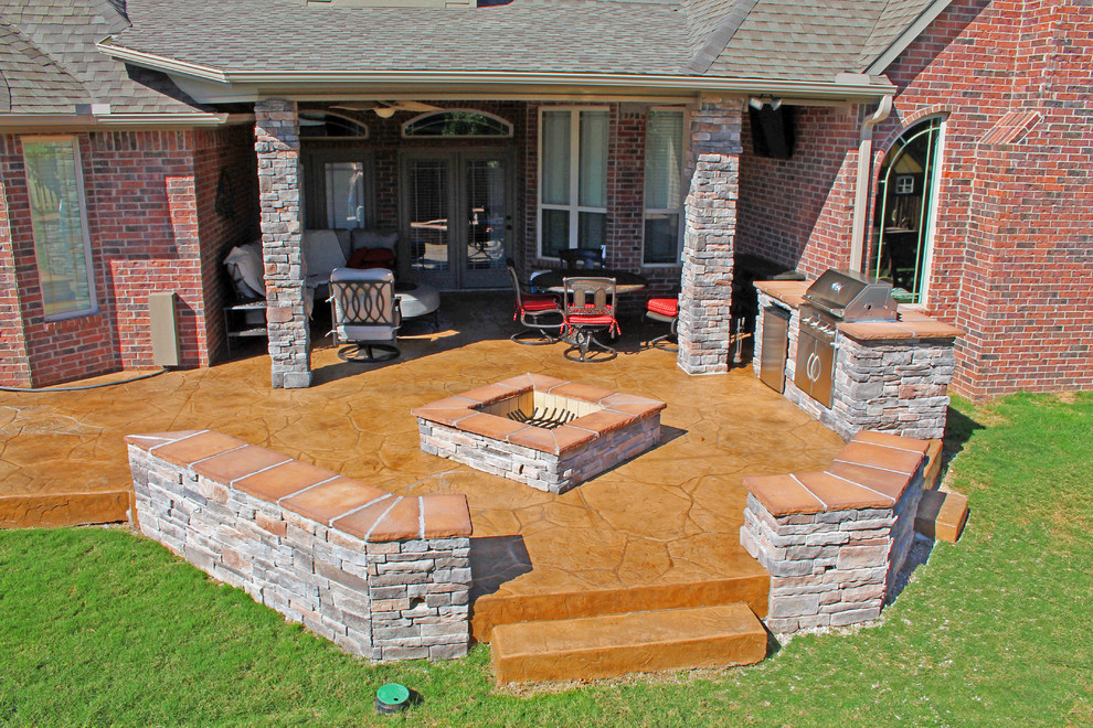 Cette photo montre une terrasse arrière chic de taille moyenne avec une cuisine d'été, du béton estampé et une extension de toiture.