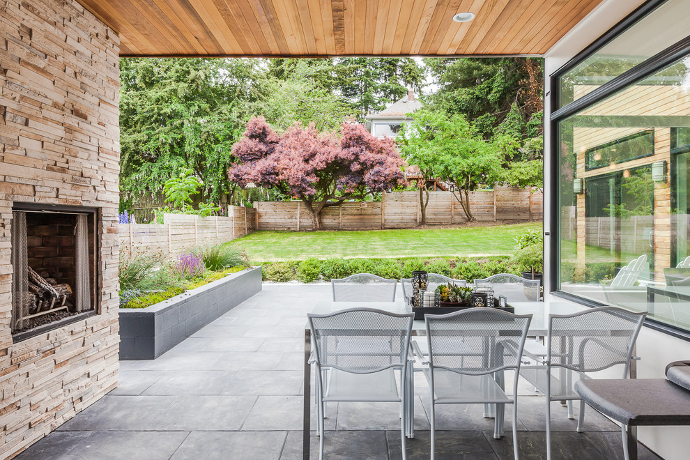 Idée de décoration pour une terrasse latérale design de taille moyenne avec un foyer extérieur et une extension de toiture.