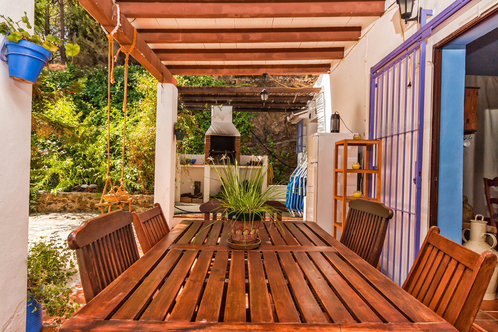 Esempio di un patio o portico mediterraneo con un focolare e una pergola