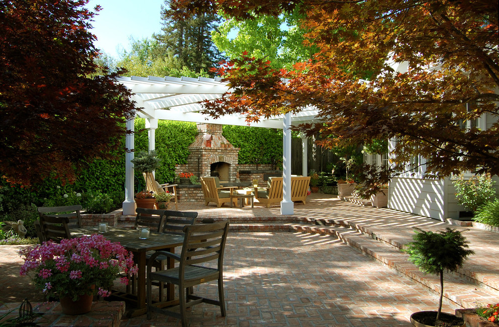 Ispirazione per un grande patio o portico tradizionale dietro casa con un caminetto, pavimentazioni in mattoni e una pergola