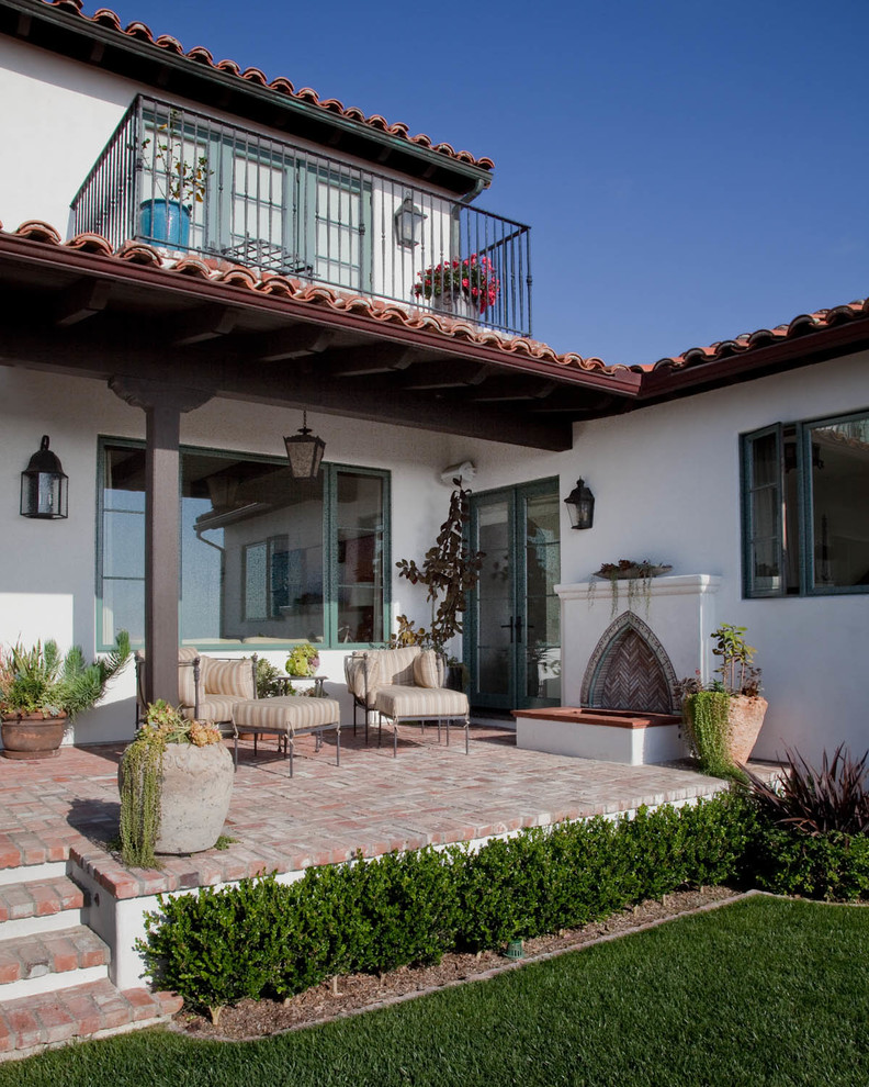 Photo of a medium sized mediterranean back patio in San Diego with brick paving and a roof extension.