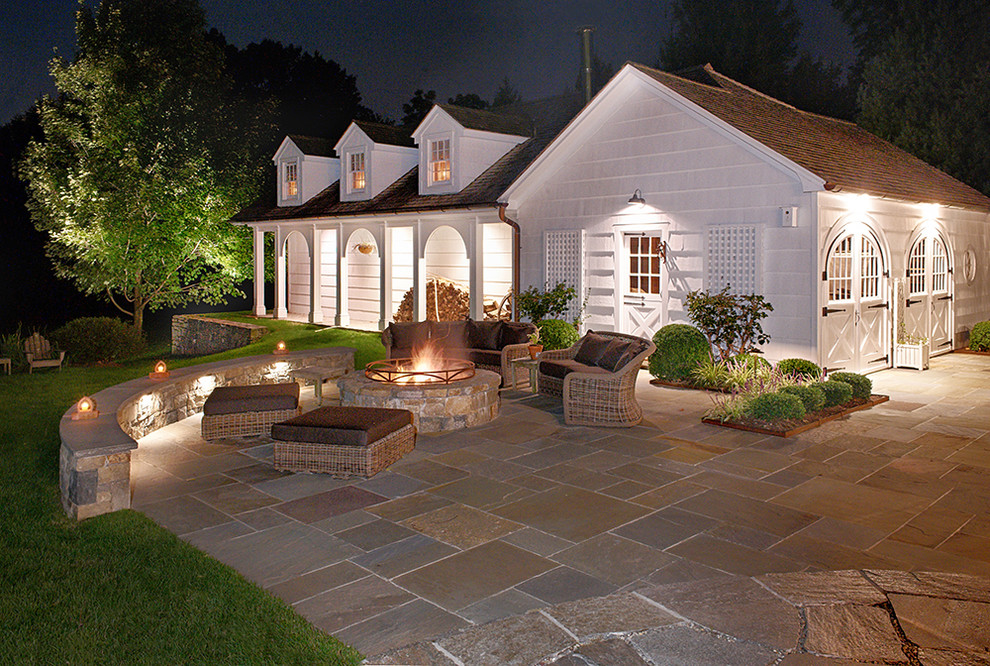 Immagine di un patio o portico country di medie dimensioni e dietro casa con un focolare, pavimentazioni in pietra naturale e nessuna copertura