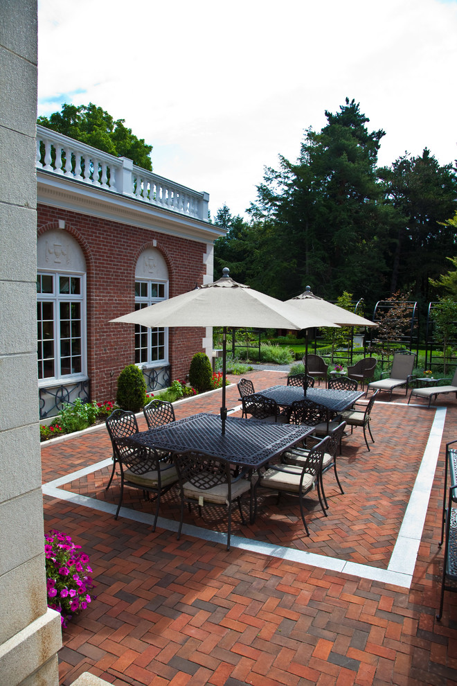 Esempio di un grande patio o portico tradizionale dietro casa con un giardino in vaso e pavimentazioni in mattoni