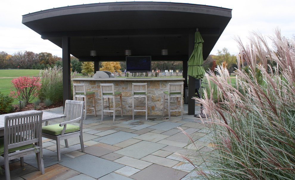 Cette photo montre une grande terrasse arrière nature avec une cuisine d'été, des pavés en pierre naturelle et un gazebo ou pavillon.