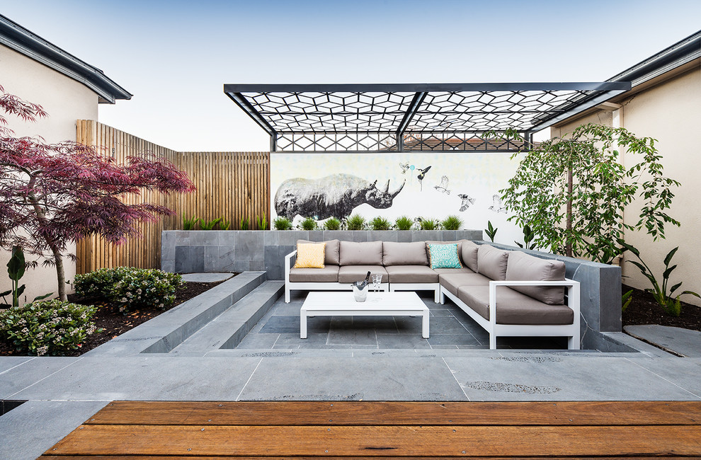 Small contemporary courtyard patio in Melbourne with natural stone paving and a pergola.