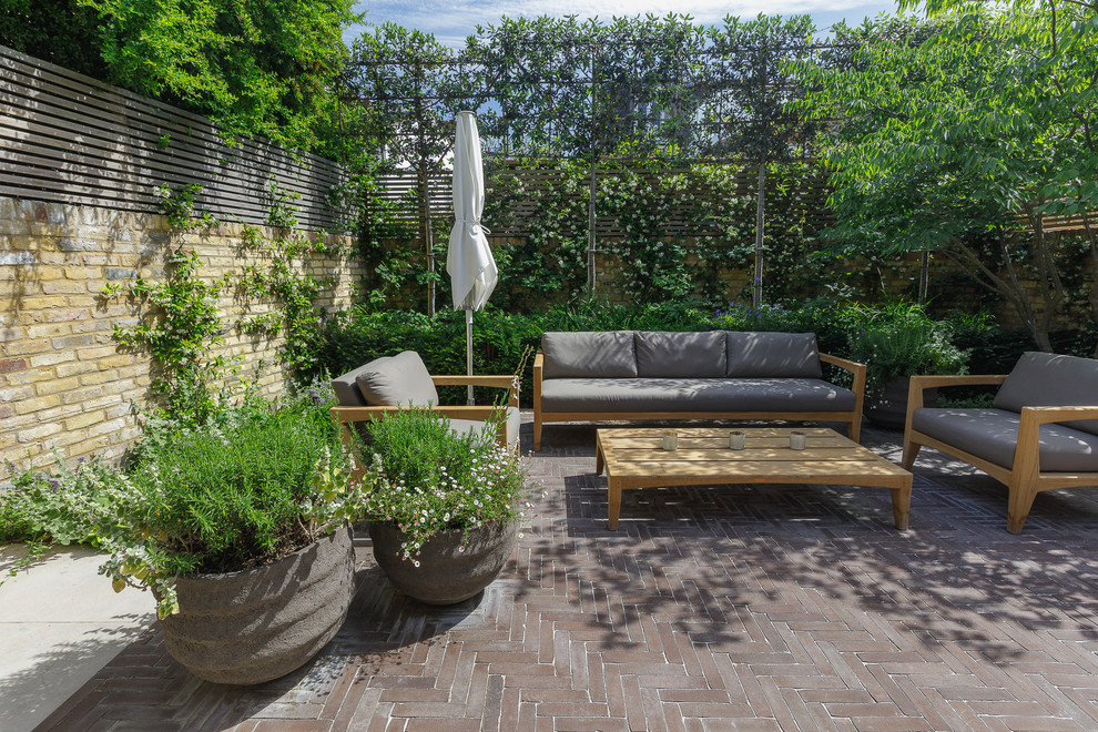 Small classic back patio in London with brick paving and no cover.