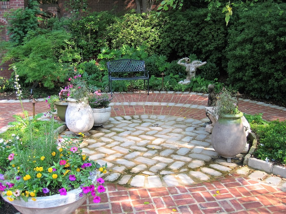 Foto de patio tradicional de tamaño medio sin cubierta en patio trasero con fuente y adoquines de ladrillo